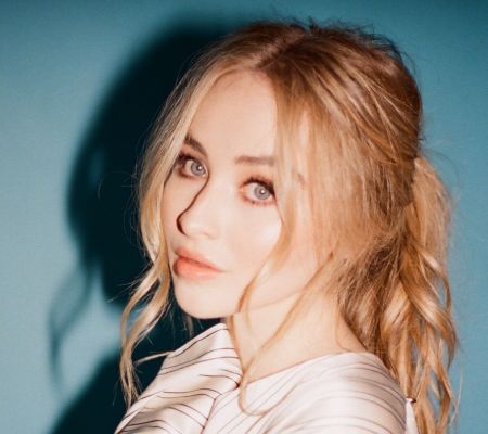 Sabrina Carpenter in a white dress poses for a picture.